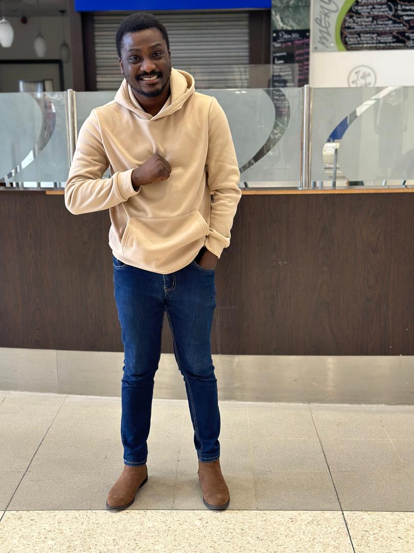 Muyiwa in a hoodie with hands pulling the wear. A brown Chelsea boot et al.