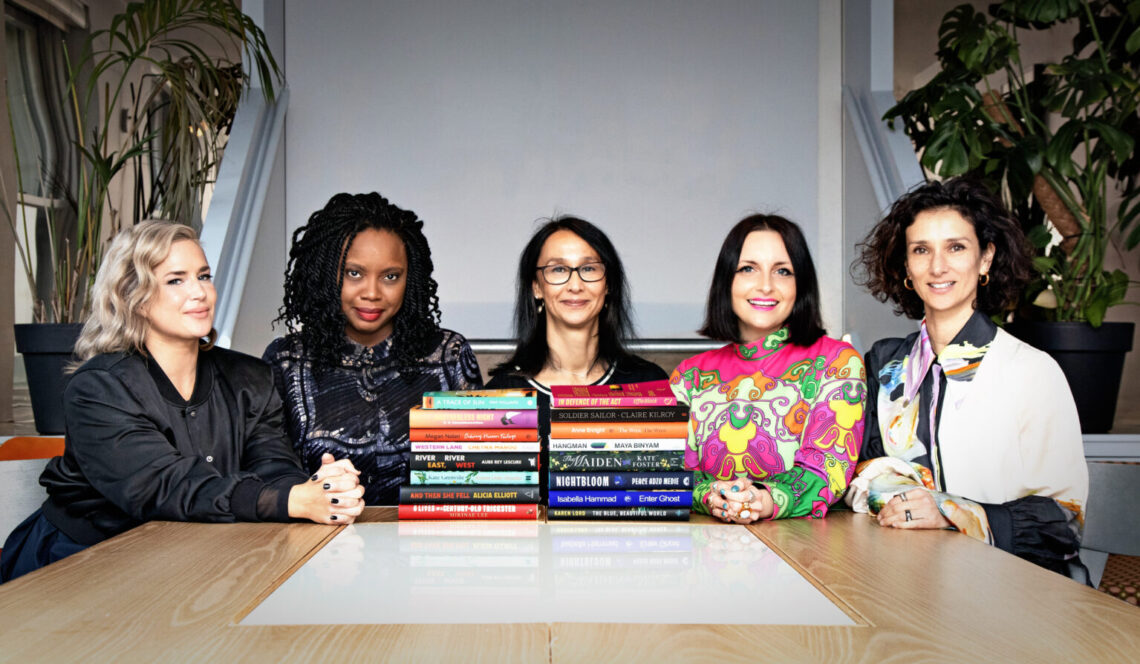 A cross-section of judges seated behind a pile of books.